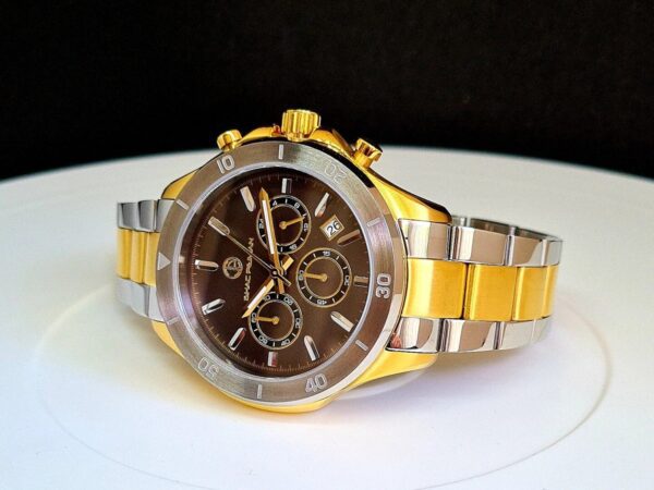 A gold and silver watch sitting on top of a white table.