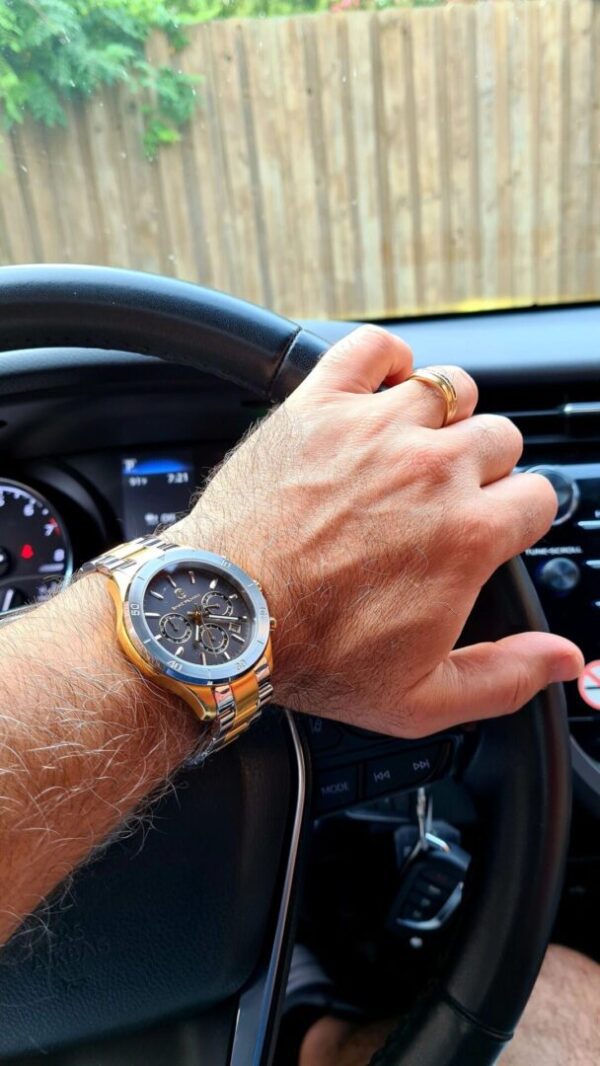 A man with his hand on the steering wheel of a car.