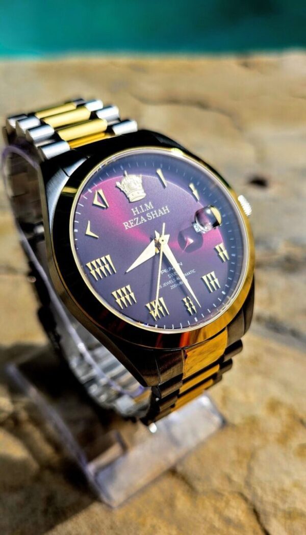 A gold and black watch sitting on top of a table.