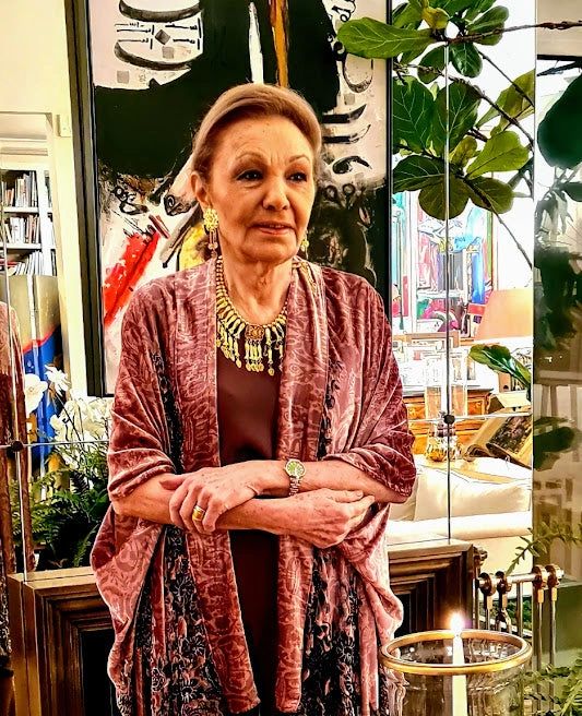 A woman standing in front of plants and a plant stand.