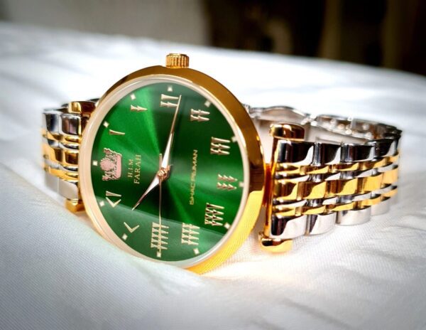 A green and gold watch sitting on top of a table.