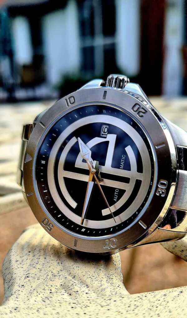 A watch is sitting on top of a wooden table.
