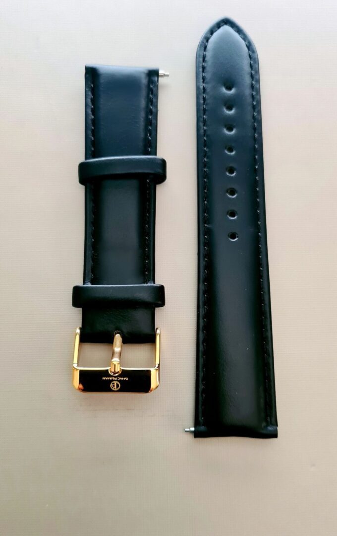 A black watch strap with gold buckle and a black band.
