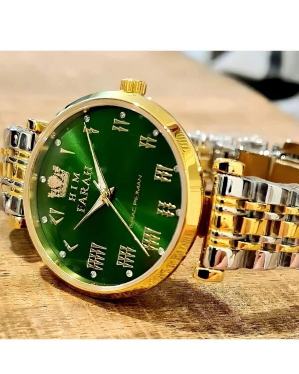 A green and gold watch sitting on top of a wooden table.