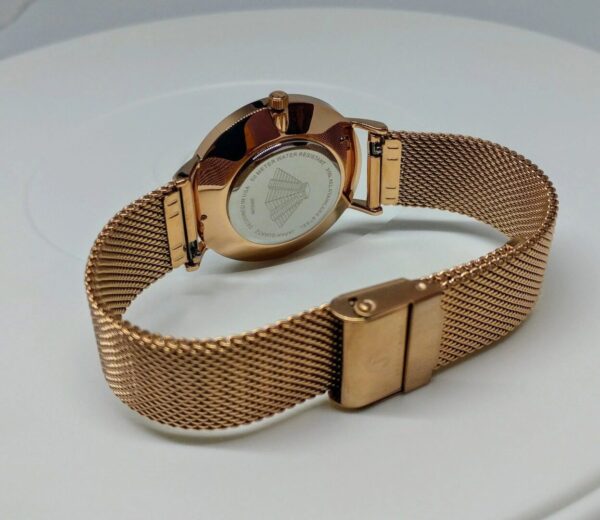 A gold watch with a mesh band on top of a table.