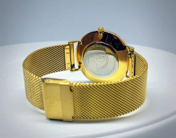 A gold watch with a mesh band on top of a table.