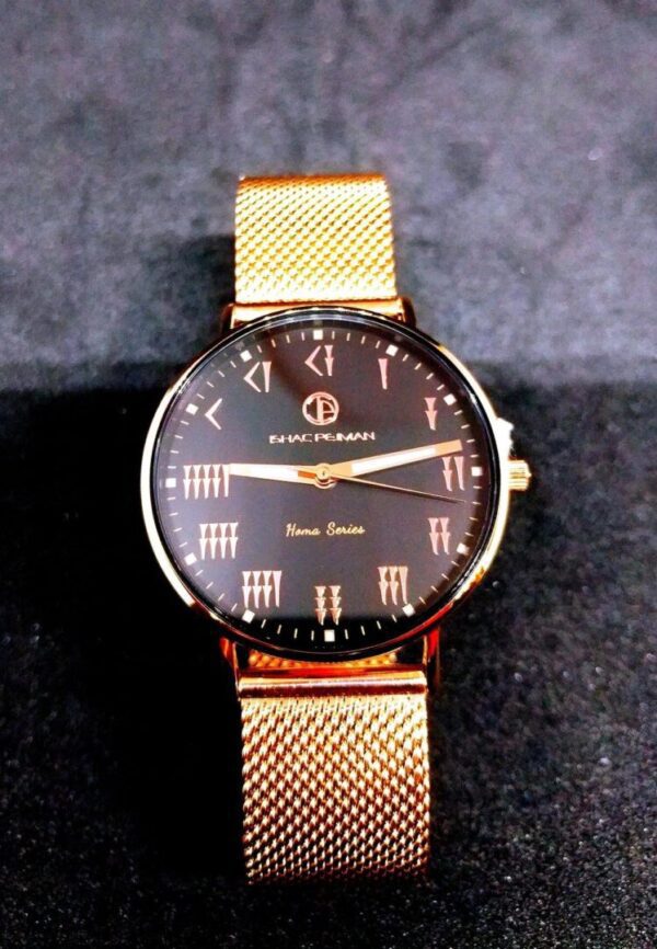 A black and gold watch on a metal mesh band.