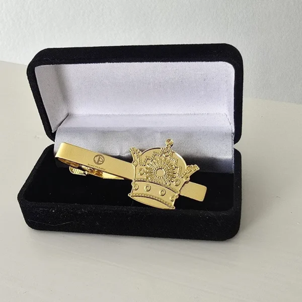 A gold tie clip in the shape of a crown.