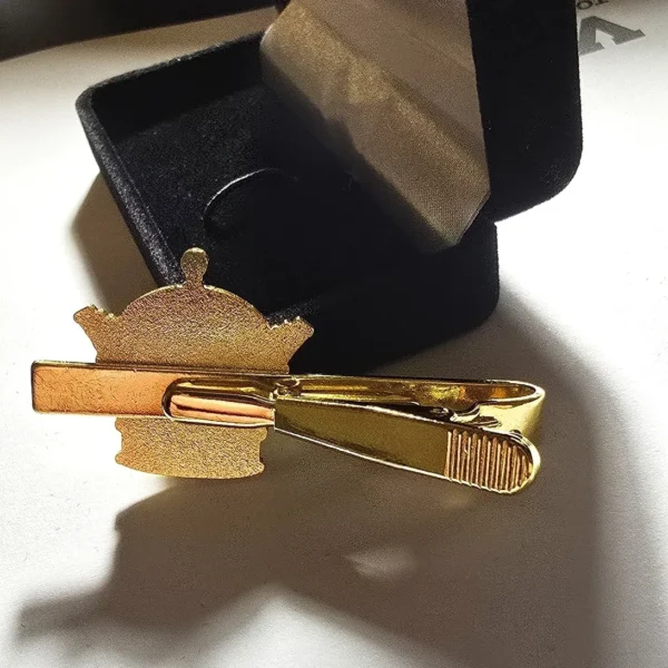 A gold tie clip in the shape of an oriental symbol.