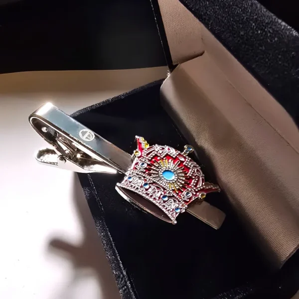 A silver tie clip with a crown on it