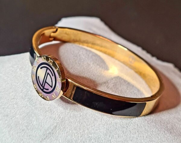 A gold bracelet with a peace sign on it.