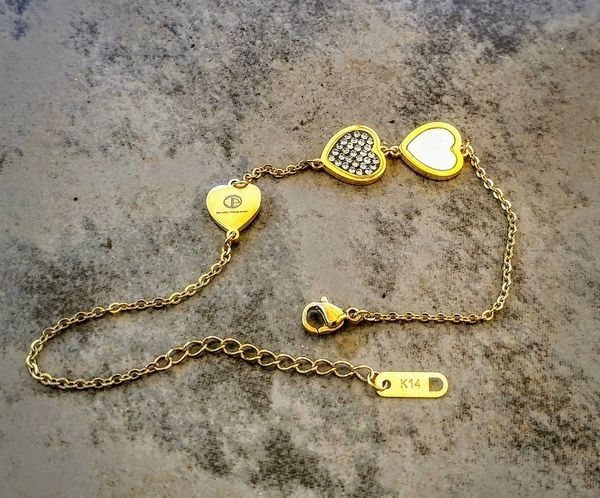 A gold chain with three hearts on it.